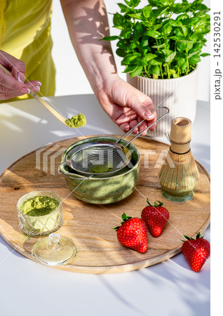 Hands Sifting Matcha Powder into Bowl with Strawberries Hands Sifting Matcha Powder into Bowl with Strawberries 142530291