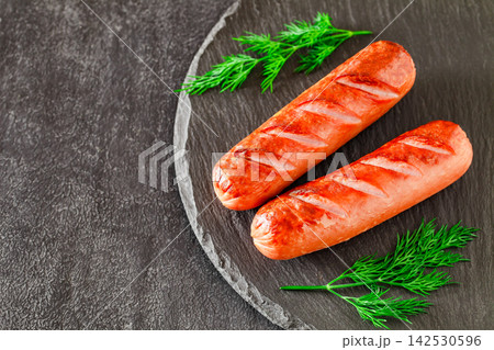 grilled sausages with herbs on a dark table 142530596