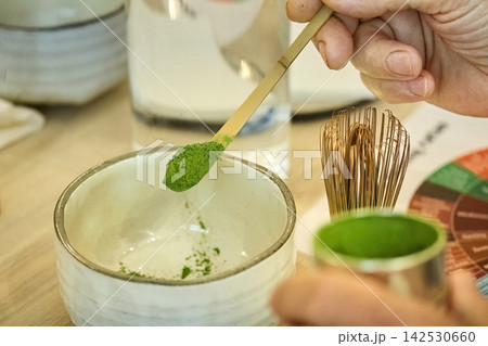 Hand scooping matcha powder into a ceramic bowl Hand scooping matcha powder into a ceramic bowl 142530660