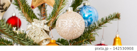 A Christmas tree stands with many colorful ornaments hanging from its branches. Each ornament shows different shapes and colors, celebrating the festive season and bringing joy to the home 142530908
