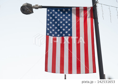 American Flag Displayed Outdoors Against Green Foliage, Patriotic United States Background American Flag Displayed Outdoors Against Green Foliage, Patriotic United States Background 142531653