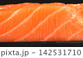 Eye level closeup shot of fresh raw salmon steak displaying parallel white fat lines and tender orange flesh 142531710