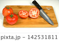 Fresh ripe red tomatoes cut in halves with chef kitchen knife on wooden cutting board, culinary cooking preparation 142531811