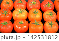 Top view of fresh ripe red tomatoes with green stems arranged in grid rows on black background, organic farm harvest produce 142531812
