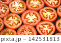 Macro shot of fresh juicy red tomato round slices arranged together, glistening cross section pulp and seed background 142531813