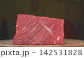Eye level closeup of raw beef steak cut showing diagonal grain muscle fibers and tender texture on wooden board 142531828