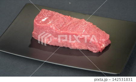 Prime cut fresh raw beef tenderloin steak portion served on modern black rectangular plate, gourmet culinary ingredient 142531831