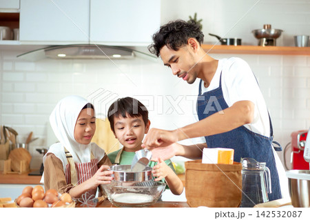 Happy Muslim father baking and sifting flour with his children in the kitchen Happy Muslim father baking and sifting flour with his children in the kitchen 142532087