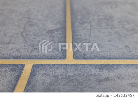Close up view of installed blue ceramic floor tiles with beige grout lines Close up view of installed blue ceramic floor tiles with beige grout lines 142532457