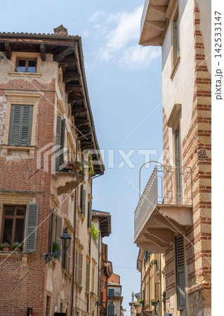 Narrow Cozy Street with Brick Historical Buildings and Balconies in Verona Old Town Center in Italy 142533147