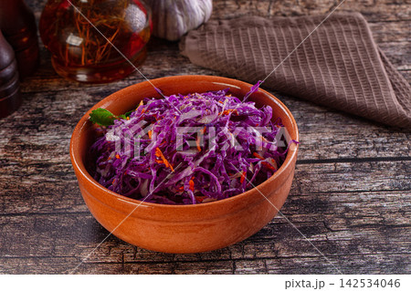 Shredded red cabbage salad in terracotta bowl on rustic wood table 142534046