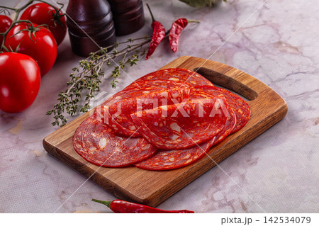 Sliced salami on wooden cutting board with fresh tomatoes and red chili peppers Sliced salami on wooden cutting board with fresh tomatoes and red chili peppers 142534079