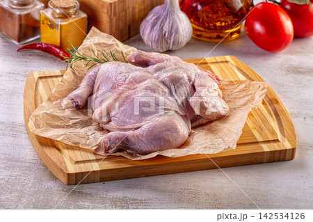 Raw whole chicken on wooden cutting board with herbs and spices Raw whole chicken on wooden cutting board with herbs and spices 142534126