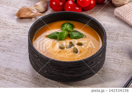 Creamy pumpkin soup in black ceramic bowl with basil and pumpkin seeds Creamy pumpkin soup in black ceramic bowl with basil and pumpkin seeds 142534156