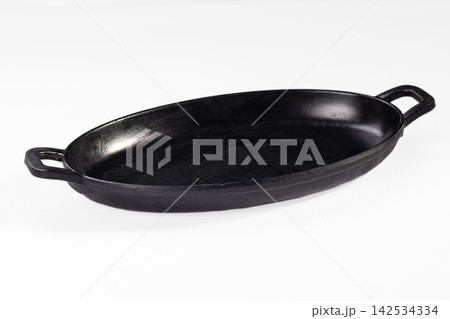 Black cast iron oval baking dish with two handles on white background Black cast iron oval baking dish with two handles on white background 142534334
