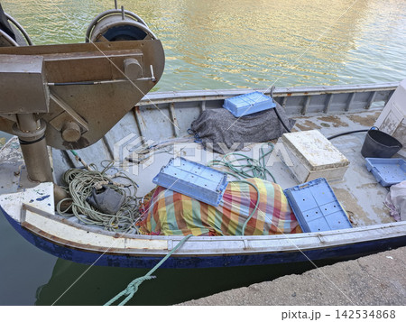 Deck of a small commercial fishing boat with equipment and crates docked in the harbor Deck of a small commercial fishing boat with equipment and crates docked in the harbor 142534868