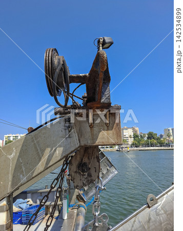 Pulley system and mounting rig of a boat's trawl crane against a blue sky 142534899