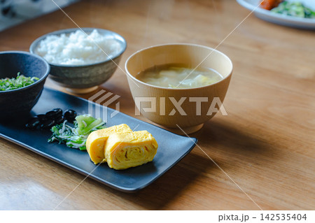 卵焼きと黒豆の和定食に、ご飯と湯気が立つ味噌汁が添えられたテーブルショット。 卵焼きと黒豆の和定食に、ご飯と湯気が立つ味噌汁が添えられたテーブルショット。 142535404