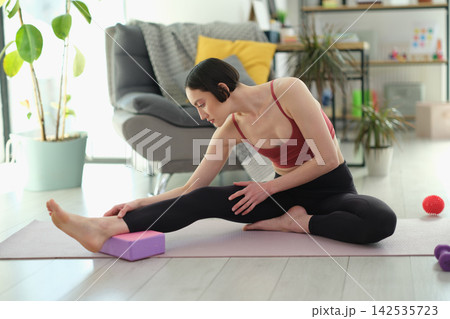Athlete practices stretching pose using purple exercise block 142535723