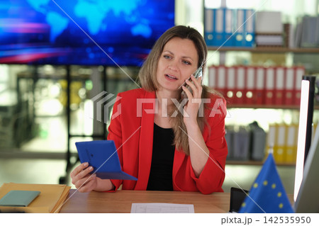 Woman agent talks on mobile phone and holds passport in office 142535950