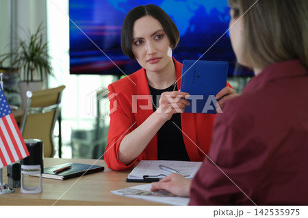 Woman counselor compares applicant face with passport photo Woman counselor compares applicant face with passport photo 142535975