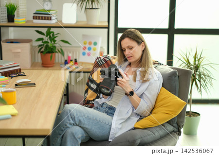 Woman reviews photos on professional camera in home office 142536067