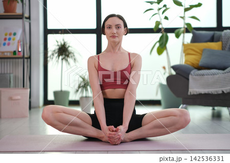 Woman practices butterfly pose during peaceful yoga session Woman practices butterfly pose during peaceful yoga session 142536331