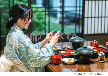 温泉旅館の懐石料理をスマホで撮影する浴衣姿の女性。旅先で楽しむ和食 142536666