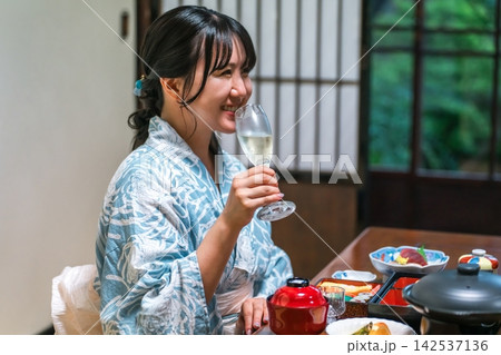 温泉旅館でシャンパンを楽しむ浴衣姿の女性。ご褒美旅行を満喫する笑顔のひととき 142537136