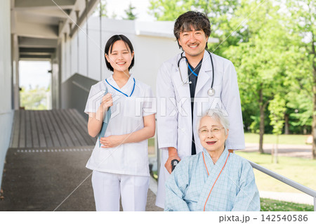 病院の廊下で車椅子のシニア入院患者に付き添う医師と看護師 病院の廊下で車椅子のシニア入院患者に付き添う医師と看護師 142540586