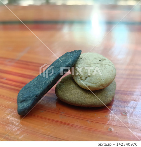 Stacked stone and dark pebble on polished wooden surface with natural texture and balance 142540970