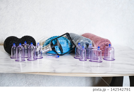 Tools for cupping therapy in a treatment room on a white table with gloves and plants present Tools for cupping therapy in a treatment room on a white table with gloves and plants present 142542791