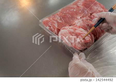 大量のお肉を小分けする女性の手元 142544492