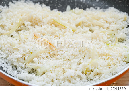 フライパンで米と玉ねぎを炒める 142545229