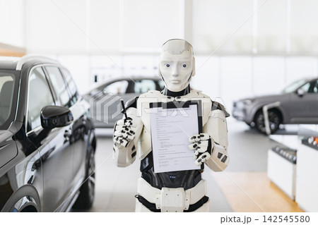 A humanoid robot stands in a car dealership holding a vehicle purchase agreement and a pen, ready to finalize a sale A humanoid robot stands in a car dealership holding a vehicle purchase agreement and a pen, ready to finalize a sale 142545580