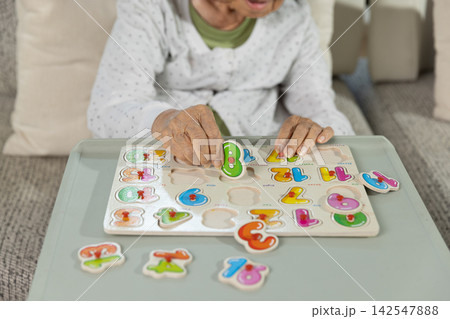 Elderly Asian Woman with Dementia Confused by Number Slide Puzzle in Nursing Home. Elderly Asian Woman with Dementia Confused by Number Slide Puzzle in Nursing Home. 142547888