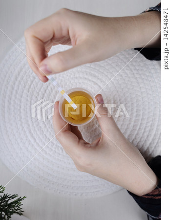 Person dipping a reagent test strip into a urine specimen container for medical analysis. Practical home diagnostic test checking health parameters and biomarkers. Person dipping a reagent test strip into a urine specimen container for medical analysis. Practical home diagnostic test checking health parameters and biomarkers. 142548471
