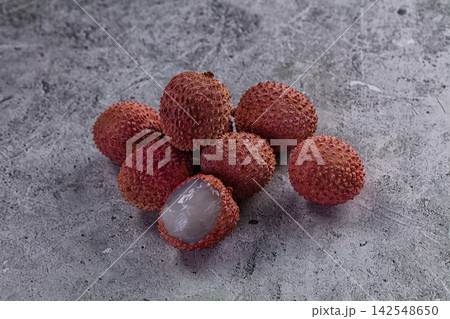 Fresh lychee fruits with one peeled on textured gray surface 142548650