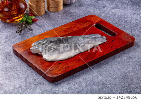 Raw seabass fillet on wooden cutting board with herbs and olive oil Raw seabass fillet on wooden cutting board with herbs and olive oil 142548656