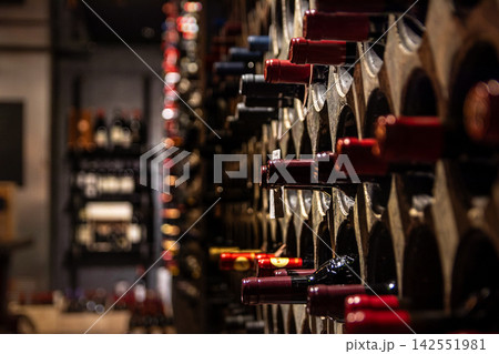 Rows of wine bottles resting in a dimly lit wine 142551981