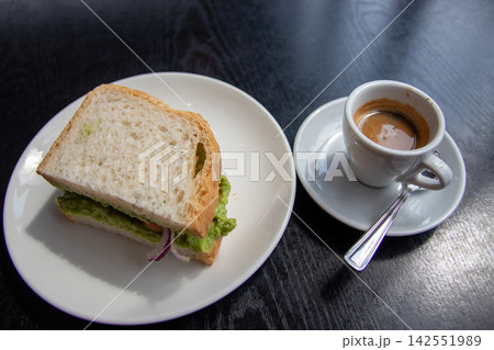 Avocado sandwich served with a cup of espresso 142551989