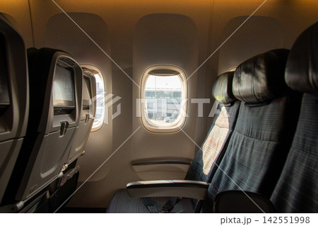 Row of empty airplane seats beside a sunlit cabin Row of empty airplane seats beside a sunlit cabin 142551998