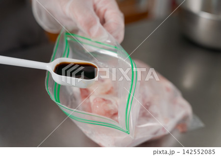 大量のお肉に味付けをするところ 142552085