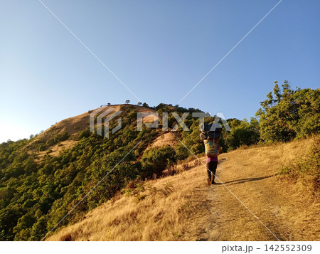 A hill-tribe porter carries a tourist belongings up on the mountain in Thailand A hill-tribe porter carries a tourist belongings up on the mountain in Thailand 142552309