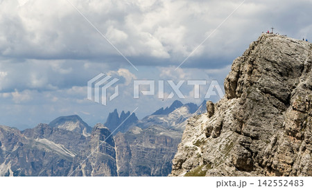 People reaching summit cross on a dolomite mountain peak, italy People reaching summit cross on a dolomite mountain peak, italy 142552483