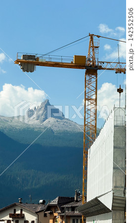 Tower crane on construction site in dolomites mountains Tower crane on construction site in dolomites mountains 142552506