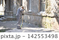 Municipal Worker Sweeping Broken Glass Near Brick Building 142553498