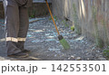 Cleaner Sweeping Broken Glass Shards with Broom Outdoors 142553501