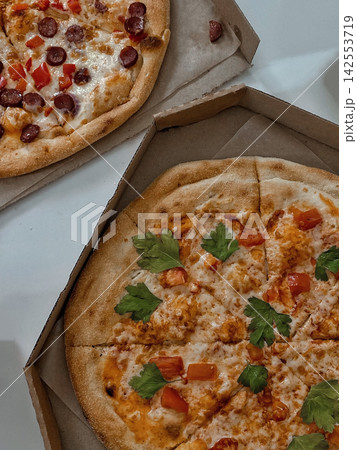 Two Fresh Pizzas in Cardboard Boxes on White Table 142553719
