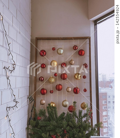Christmas ornaments hanging on wall grid near window, soft daylight cozy interior scene Christmas ornaments hanging on wall grid near window, soft daylight cozy interior scene 142554924